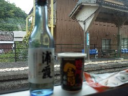 牟岐駅停車中の汽車の窓縁より車窓の風景を楽しむ酒瓶の写真