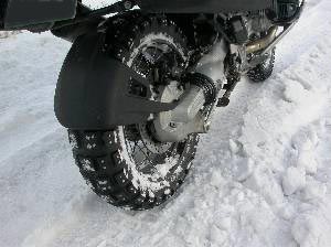 雪道に食い込む大型バイクのスパイクタイヤの写真