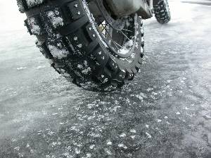 アイスバーンに刺さる大型バイクのスパイクタイヤの写真